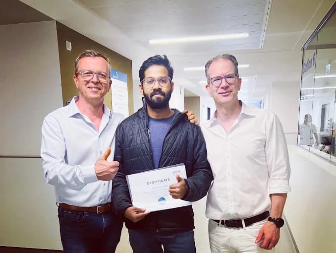 Dr. Adarsh displaying a certificate with two colleagues