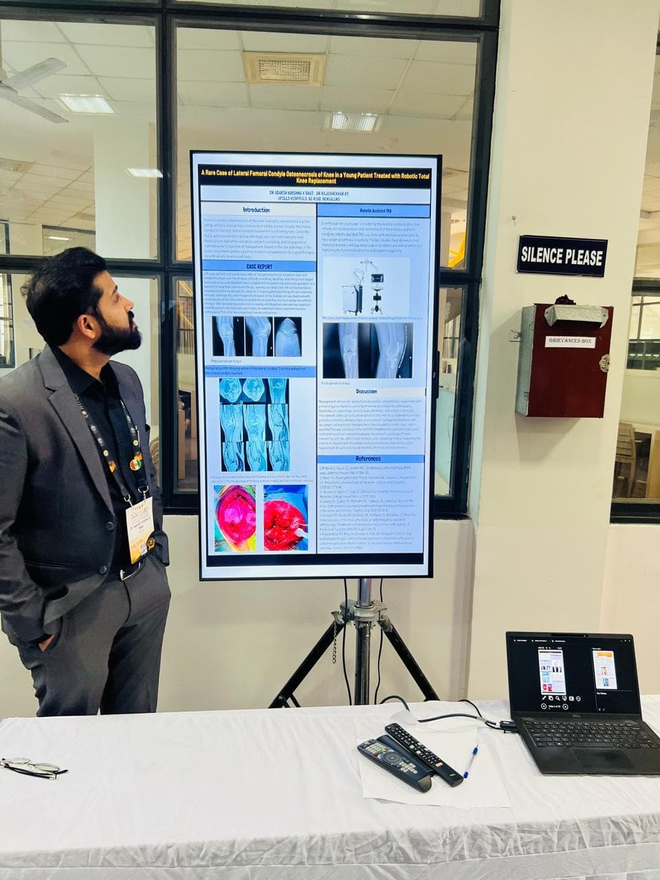 Dr. Adarsh beside a research poster about robotic knee replacement